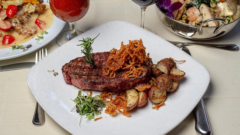 Steak entree topped with frizzled onions and a side of potatoes