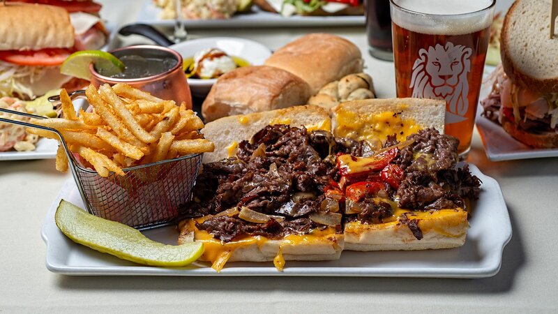 Cheesesteak sandwich with side of french fries and pickle